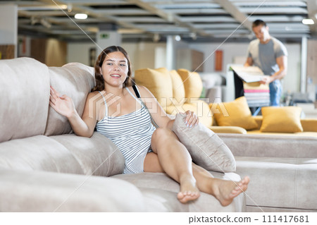 In furniture store,young girl is sitting on sofa with ottoman In furniture store,young girl is sitting on sofa with ottoman 111417681