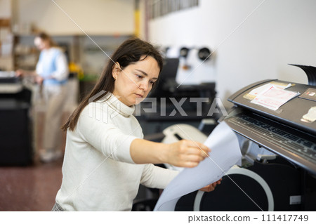 Woman employee of printing house works on modern printer Woman employee of printing house works on modern printer 111417749