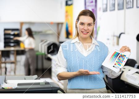 Woman employee of printing shop holds color chart in her hands Woman employee of printing shop holds color chart in her hands 111417753