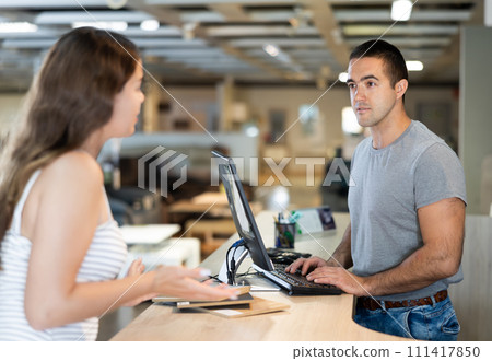 Salesman of furniture showroom advising female buyer on assortment 111417850