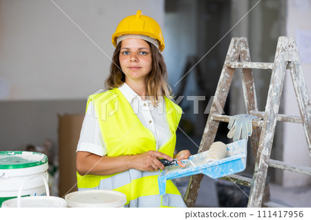 Cheerful woman builder holding paint roller and tray, home improvement works 111417956