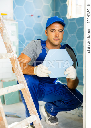 Worker laying tile in bathroom Worker laying tile in bathroom 111418046