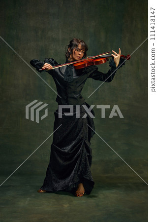Dynamic pose of passionate female musician, young woman, violinist in black attire, playing violin with intense expression on vintage green background Dynamic pose of passionate female musician, young woman, violinist in black attire, playing violin with intense expression on vintage green background 111418147