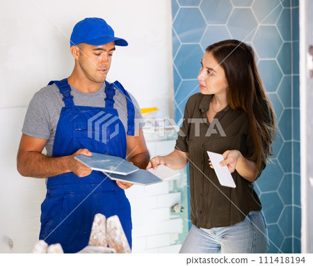Worker talking with woman about bathroom tile Worker talking with woman about bathroom tile 111418194