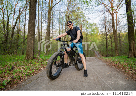 Man on a fatbike in the woods. Pleasant sports hobby. Concept of a healthy lifestyle. 111418234