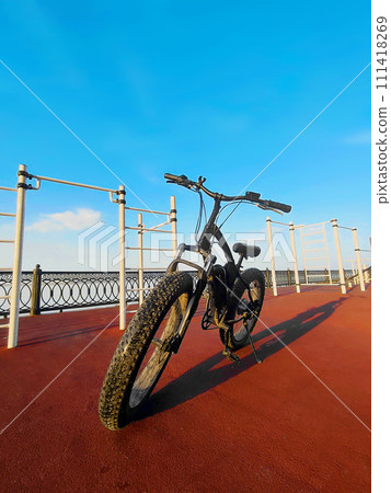 An electric bike on the sports field. Black fat bike with thick wheels. Concept of a healthy lifestyle. An electric bike on the sports field. Black fat bike with thick wheels. Concept of a healthy lifestyle. 111418269