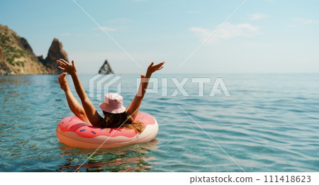 Summer vacation woman in hat floats on an inflatable donut mattress. Happy woman relaxing and enjoying family summer travel holidays travel on the sea. 111418623