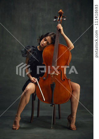 Elegant beautiful woman, cellist in moment of calmness sitting with eyes closed, connecting deeply with the music. Deep enjoyment of sounds 111418693
