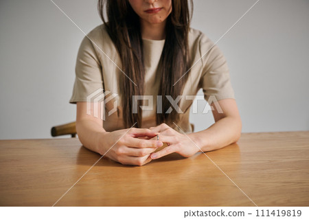 A woman in her 30s taking off her wedding ring A woman in her 30s taking off her wedding ring 111419819