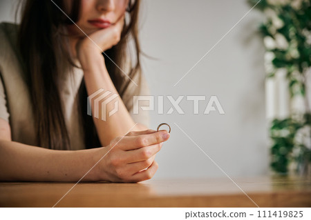 A woman in her 30s taking off her wedding ring A woman in her 30s taking off her wedding ring 111419825