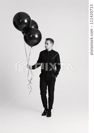 elegant caucasian man with bunch of black air balloons on white background. black and white elegant caucasian man with bunch of black air balloons on white background. black and white 111420713