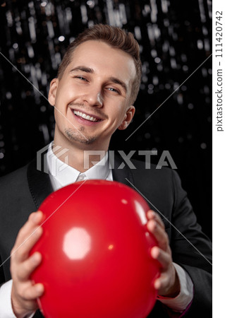 caucasian man in black jacket with red air balloon on dark glitter background. new year party 111420742