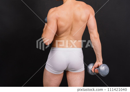 Shirtless bodybuilder holding dumbell and showing his muscular arms. 111421040
