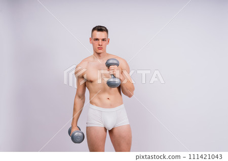 Shirtless bodybuilder holding dumbell and showing his muscular arms. 111421043