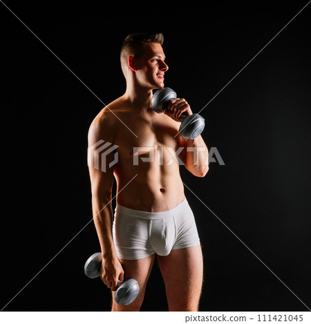 Shirtless bodybuilder holding dumbell and showing his muscular arms. 111421045