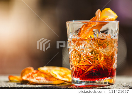 Delicious old fashion cocktail in the etched glass with ice and orange slices. Shallow dof. 111421637