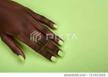 African American womans hand with long nails and green color manicure against green background African American womans hand with long nails and green color manicure against green background 111421838