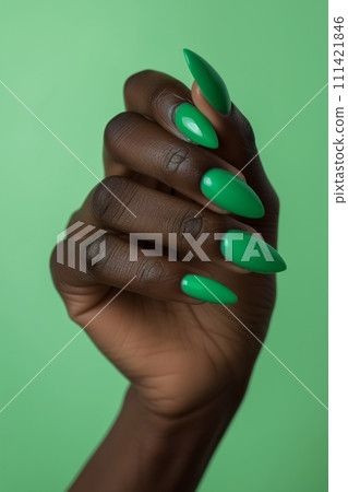 African American womans hand with long nails and grass green color manicure against green background 111421846