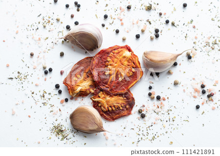 Dried tomatoes with black pepper and garlic on a white background. Dried tomatoes with black pepper and garlic on a white background. 111421891