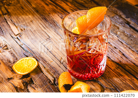 Delicious old fashion cocktail in the etched glass with ice and orange slices, dark wooden background. Shallow dof 111422070
