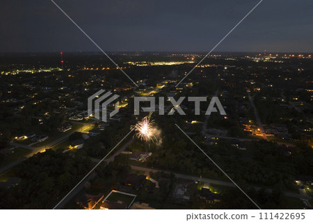 Aerial view of bright fireworks exploding with colorful lights over suburban houses in residential area on US Independence day holiday 111422695