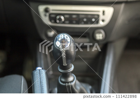 Luxurious car black leather interior. Close-up detail of handbrake manual brake and gearshift stick on blurred dashboard background. Transportation, design, modern technology concept. Luxurious car black leather interior. Close-up detail of handbrake manual brake and gearshift stick on blurred dashboard background. Transportation, design, modern technology concept. 111422898