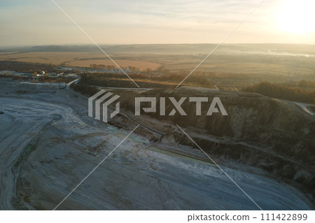 Aerial view of open pit mining site of limestone materials for construction industry with excavators and dump trucks Aerial view of open pit mining site of limestone materials for construction industry with excavators and dump trucks 111422899