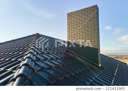 Closeup of brick chimney on house roof top covered with ceramic shingles. Tiled covering of building Closeup of brick chimney on house roof top covered with ceramic shingles. Tiled covering of building 111422901