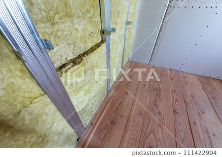 Wall of a room under renovation with mineral rock wool insulation and metal frame prepared for drywall plates. Wall of a room under renovation with mineral rock wool insulation and metal frame prepared for drywall plates. 111422904