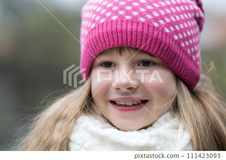 Pretty child girl in warm knitted winter clothes outdoors. 111423093