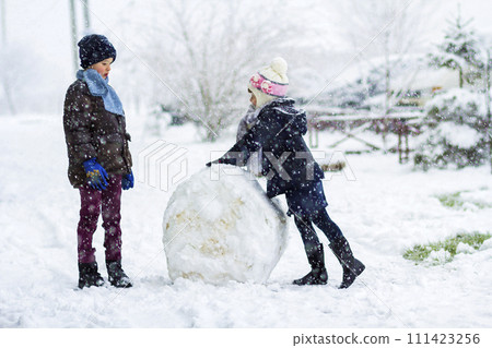 Children boy and girl outdoors in snowy winter are making a big snowman 111423256