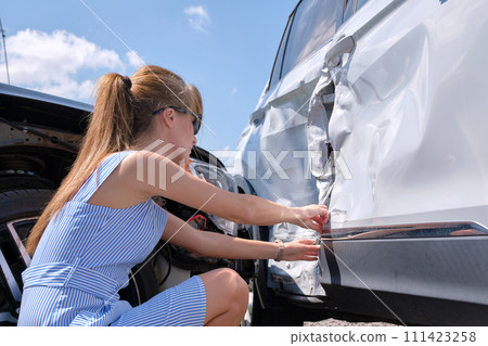 Stressed woman driver sitting on street side shocked after car accident. Road safety and insurance concept 111423258