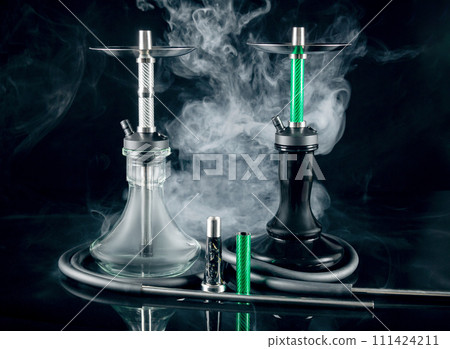 Two modern hookahs with smoke on a black mirror background. Two modern hookahs with smoke on a black mirror background. 111424211