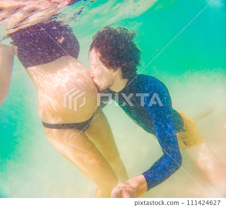 Amidst the tranquil turquoise sea, a pregnant woman and her husband share a serene moment, celebrating the beauty of impending parenthood in the gentle waves Amidst the tranquil turquoise sea, a pregnant woman and her husband share a serene moment, celebrating the beauty of impending parenthood in the gentle waves 111424627