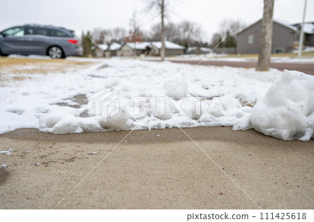 Residential sidewalk with section that has been cleared of snow next to a covered path. Residential sidewalk with section that has been cleared of snow next to a covered path. 111425618