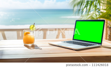 Laptop with green screen on a table by the beach with a tropical cocktail, palm trees, and ocean view portraying a relaxed work environment 111426018
