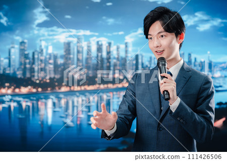 一個穿著西裝的男人在戶外用麥克風講話 一個穿著西裝的男人在戶外用麥克風講話 111426506