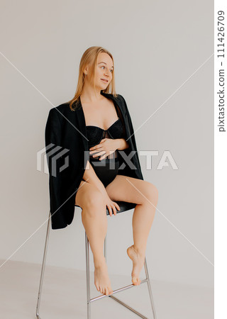Body of a pregnant woman in black underwear on a white background. Fetal period, hormonal changes in a pregnant girl. Gynecology Body of a pregnant woman in black underwear on a white background. Fetal period, hormonal changes in a pregnant girl. Gynecology 111426709