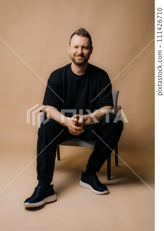 Portrait of smiling mature man standing on beige background. 111426710