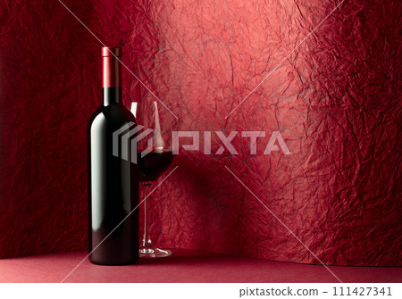 Bottle and glass of red wine on a red background. Bottle and glass of red wine on a red background. 111427341