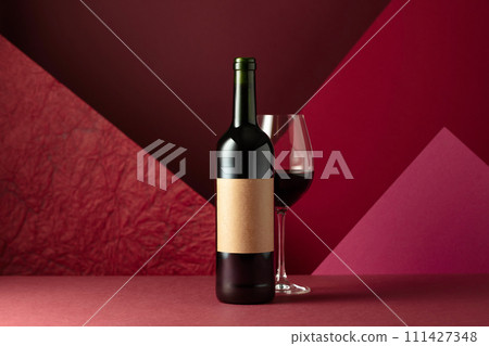 Bottle and glass of red wine on a red background. Bottle and glass of red wine on a red background. 111427348
