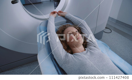 Female patient lies at MRI or CT or PET scan machine bed 111427408