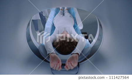 Female patient lies in MRI or CT scanner machine waiting for the procedure Female patient lies in MRI or CT scanner machine waiting for the procedure 111427564