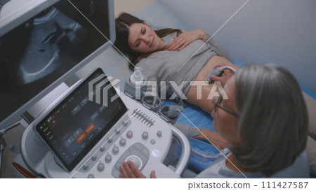 Female doctor conducts ultrasound diagnostics using sonography machine Female doctor conducts ultrasound diagnostics using sonography machine 111427587