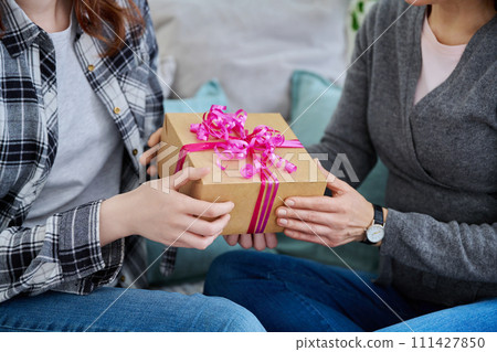 Concept gift, holidays, hands of two women older and younger with packed gift box 111427850