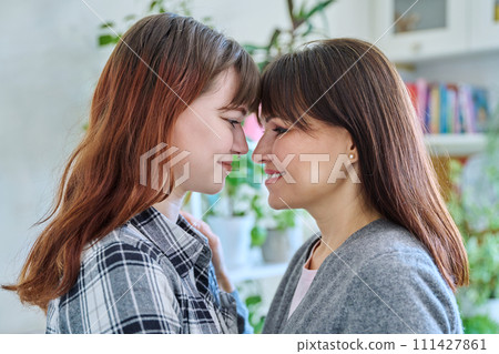 Close-up profile portrait of mother and daughter 18-20 years old. 111427861