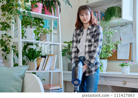Young teenage female doing vacuuming at home 111427863