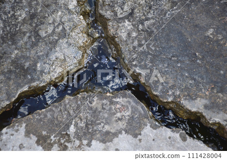 a deep crack in the road surface is filled with water after rain a deep crack in the road surface is filled with water after rain 111428004