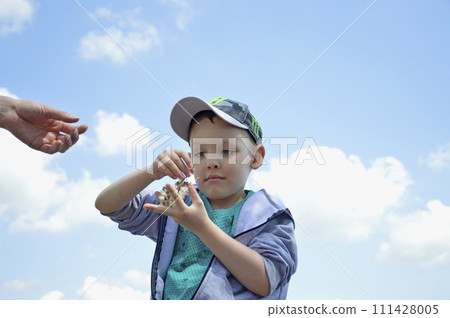 a boy with an acacia inflorescence in his hands against a background of blue 111428005