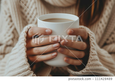 Female hands with a mug of beverage. Young woman holding cup of tea or coffee in the morning sunlight. Generative AI Female hands with a mug of beverage. Young woman holding cup of tea or coffee in the morning sunlight. Generative AI 111428489